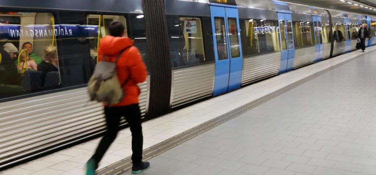 Tunnelbanetåg med stängda dörrar och passagerar på plattformen, vid station Rådmansgatan i Stockholm, Sverige.